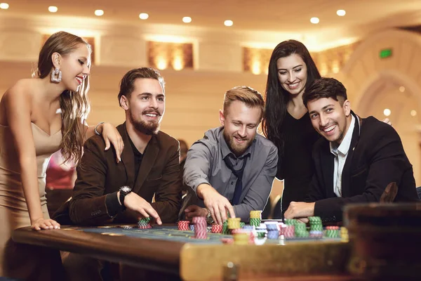 Cheerful group of friends enjoys winning poker roulette in a casino. — Stock Photo, Image