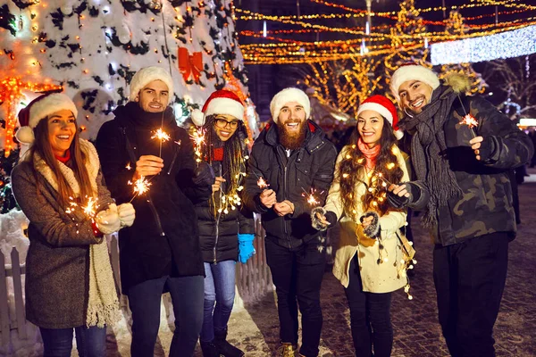 Boldog barátok csillagszórókkal egy karácsonyi vásáron — Stock Fotó