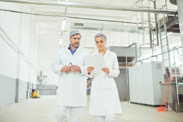 Twee technologen in lab jassen en maskers in de fabriek. — Stockfoto