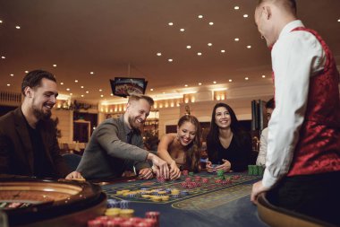 Mutlu insanlar kumarhanede rulet pokerinde kumar oynuyorlar.