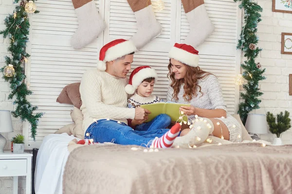 Rodina čte knížkuv domě s vánočním stromečkem. — Stock fotografie