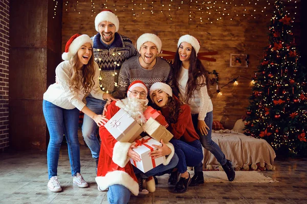 Amigos en Santas sombreros cambian regalos en la fiesta de Navidad — Foto de Stock
