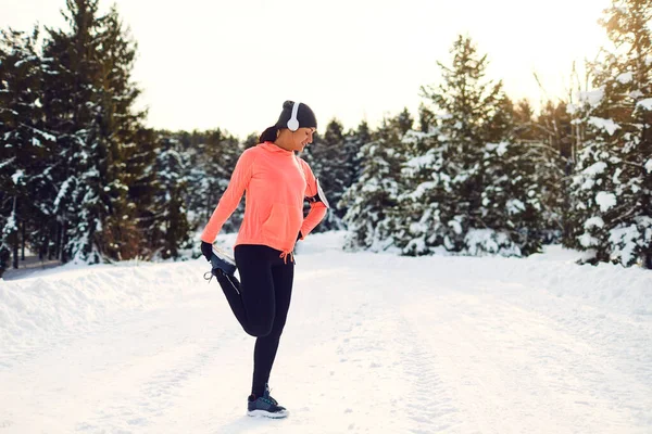 Young woman stretching before running in the winter park — Stock Photo, Image
