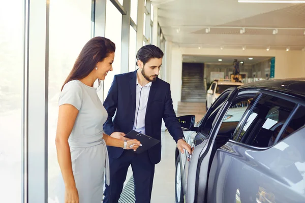 Mladá žena kupuje nové auto v autosalonu — Stock fotografie