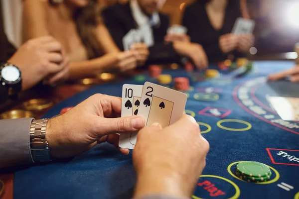 Mains d'un joueur de poker vérifiant les cartes dans un casino . — Photo