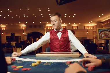 Kumarhanedeki bir masada krupiyenin elinde poker kartları var..