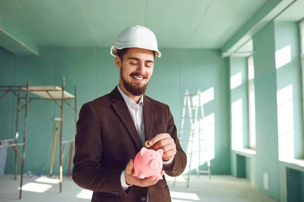 The builder foreman is holding a piggy bank in his hand. — Stock Photo, Image