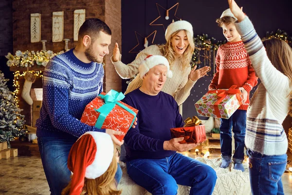 Een grote familie in een kamer geeft geschenken met Kerstmis. — Stockfoto