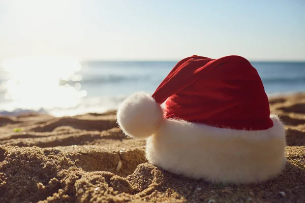 Sombrero de Santa Claus en la playa junto al mar . — Foto de Stock