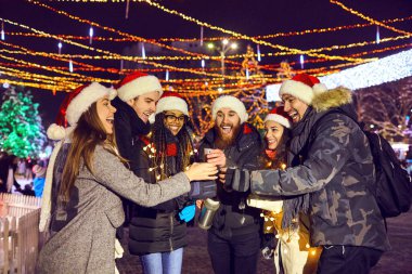 Bir grup arkadaş Noel 'de bir panayırda sıcak çay içiyor.