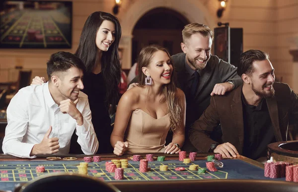 Des amis heureux jouent à la roulette dans un casino . — Photo