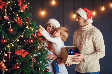 Tatil ağacını süsleyen çocukla güzel bir çift.