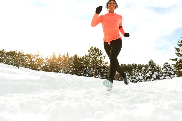 Smiling healthy woman jogging in snowy forest — Stock Photo, Image