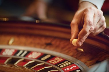Hand of a croupier on a roulette whell in a casino. clipart