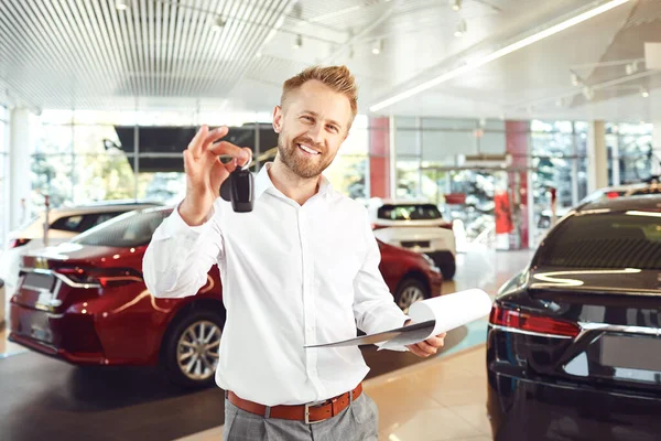 Um negociante de carro em pé em um showroom. — Fotografia de Stock