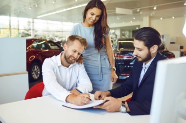 Gülümseyen adam ve kadın araba galerisinden araba alırlar..