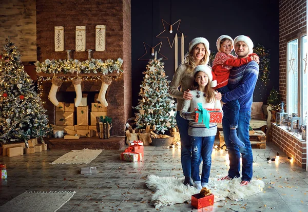 La familia en los sombreros de Santas decora el árbol de Navidad en casa en Navidad. — Foto de Stock