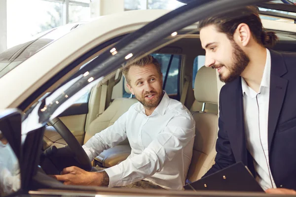 Auto revendedor mostra um carro novo para um homem — Fotografia de Stock