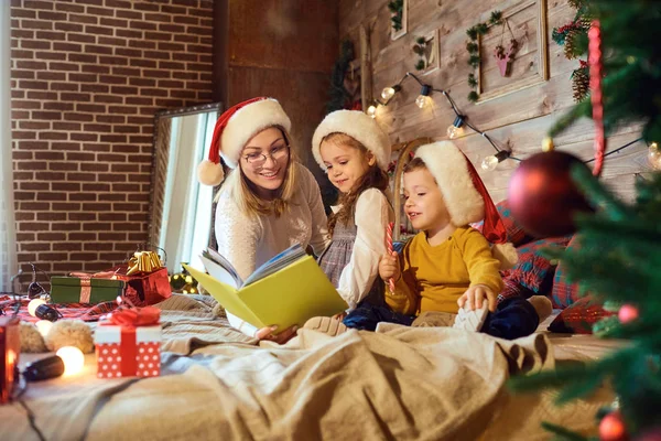 Mom in reads a book to children in the room. — Stock Photo, Image