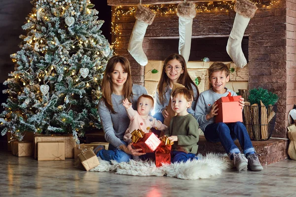 Moeder met kinderen met geschenken bij de open haard met Kerstmis. — Stockfoto