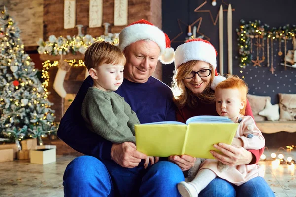 Οι παππούδες διαβάζουν ένα βιβλίο στα παιδιά τα Χριστούγεννα. — Φωτογραφία Αρχείου