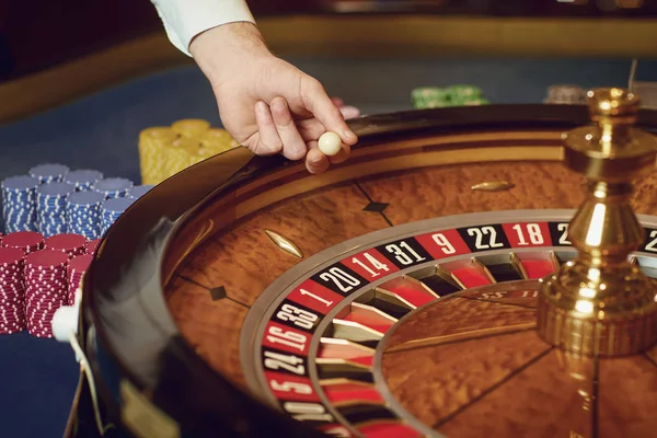 Χέρι ενός κρουπιέρη με μια μπάλα σε έναν τροχό ρουλέτας κατά τη διάρκεια ενός παιχνιδιού σε καζίνο. — Φωτογραφία Αρχείου