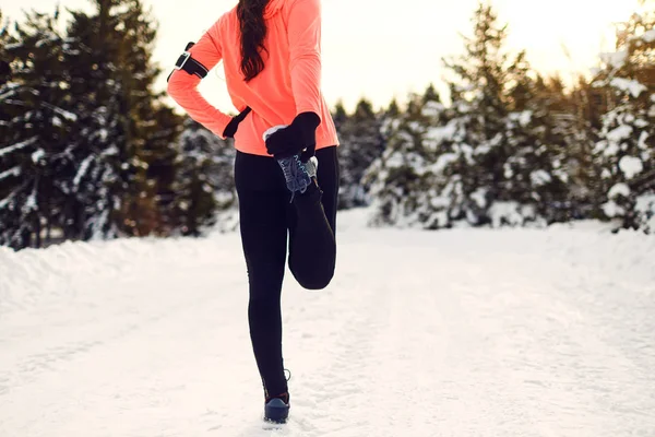 Young woman stretching before running in the winter park — Stockfoto