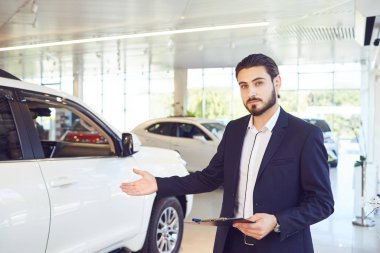 Bir araba satıcısı showroom'da araba gösterir. Oto iş.