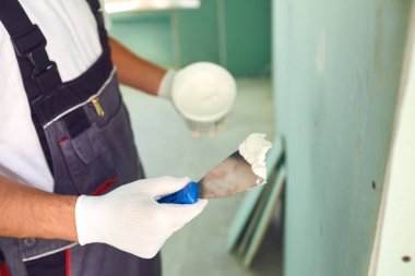 İnşaat alanındaki bir inşaat sahasının duvarına alçı yapıştıran işçi.