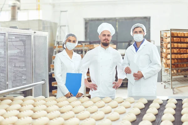 Tecnólogo e padeiro inspecionar a linha de produção de pão na padaria — Fotografia de Stock