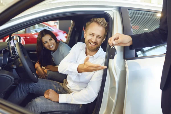 Um casal feliz comprou um carro novo em um showroom do carro . — Fotografia de Stock