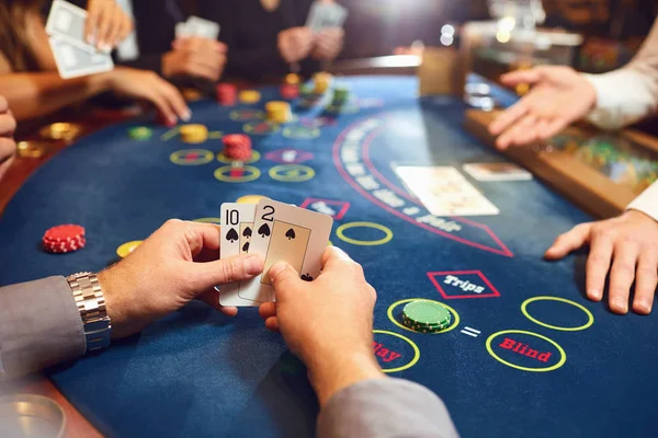 Mãos fechadas de um jogador de poker verificando cartas em um cassino . — Fotografia de Stock