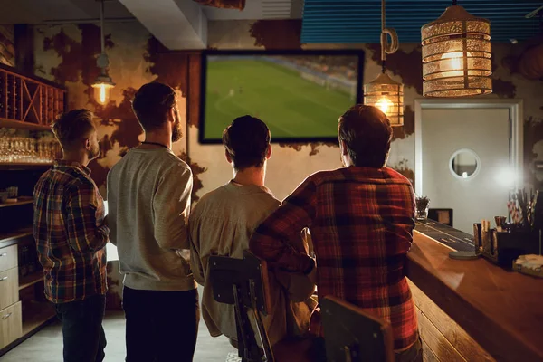 En grupp människor tittar på tv fotboll i en sportbar. — Stockfoto