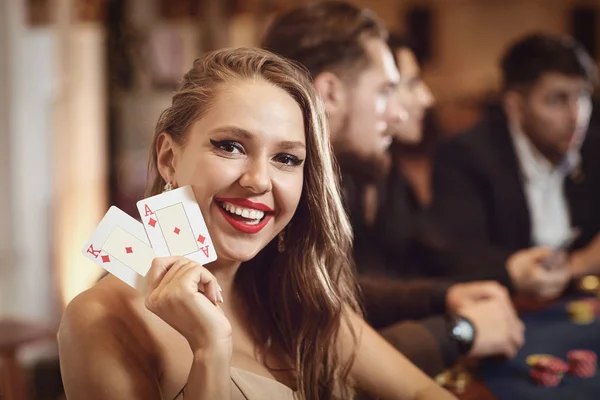 Flicka med kort i händerna ler åt att vinna poker i ett kasino. — Stockfoto