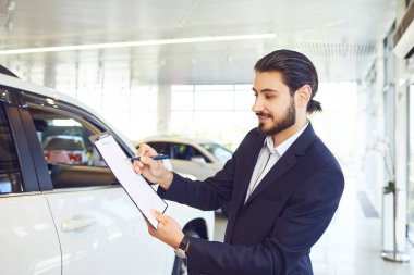Bir araba satıcısı bir araba satışı ile ilgili belgeleri tutuyor.