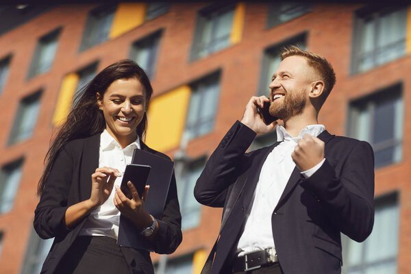 Businesspeople smiling talking on the phone on the background of a business building