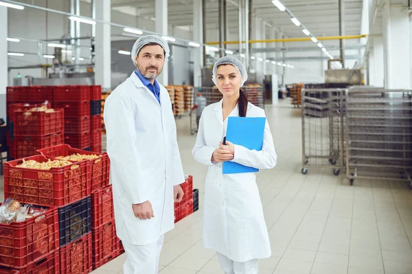 Collega 's technologen in wit uniform bij de productie van voedsel. — Stockfoto