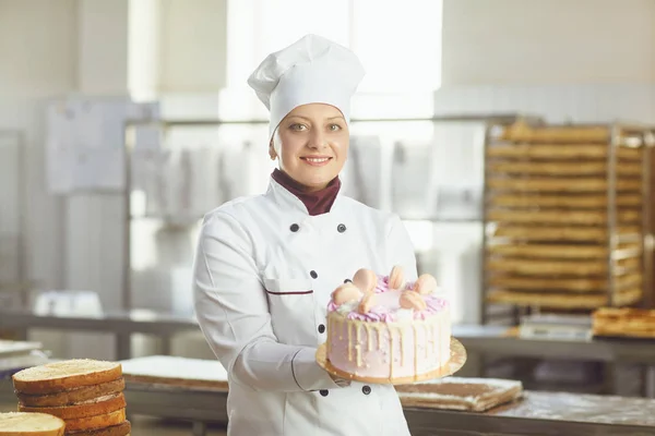 Pastelero con pastel en la mano en la panadería . — Foto de Stock