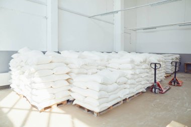 Fabrika depolamada paletler üzerinde katlanmış beyaz Çantalar.