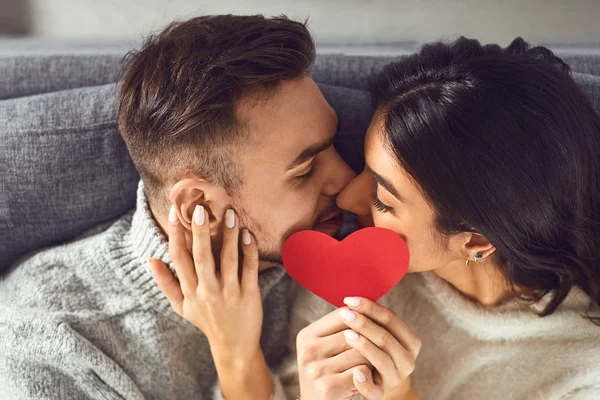 Día de San Valentín. Pareja cariñosa con corazones en la mano besos en la habitación —  Fotos de Stock