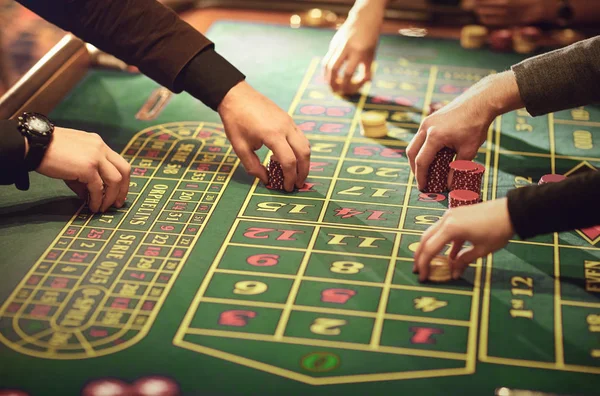 Des mains de gens mettent des jetons sur la table de roulette dans un casino . — Photo