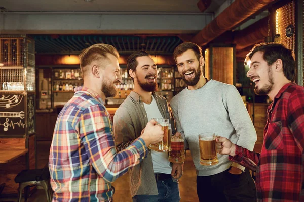 Groep gelukkige vrienden klinkende glazen met bier in een sportbar. — Stockfoto