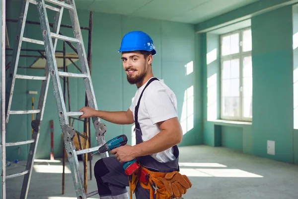Строитель-подрядчик бородатый мужчина в шлеме улыбается, стоя на стройке . — стоковое фото