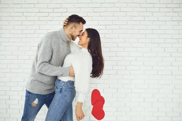 Concert Valentines Day. Young couple kissing with hearts in hands on a white brick background — 스톡 사진