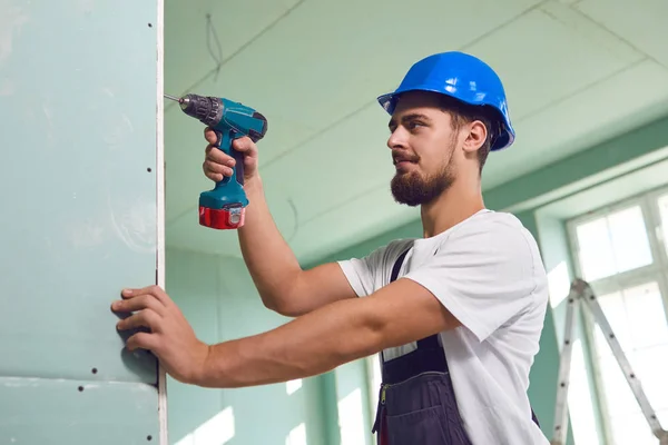 Trabalhador construtor instala gesso placa drywall em uma construção — Fotografia de Stock