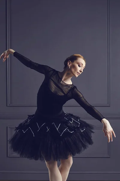 Ballerina in a black tutu posing on a black background. — Stock Photo, Image