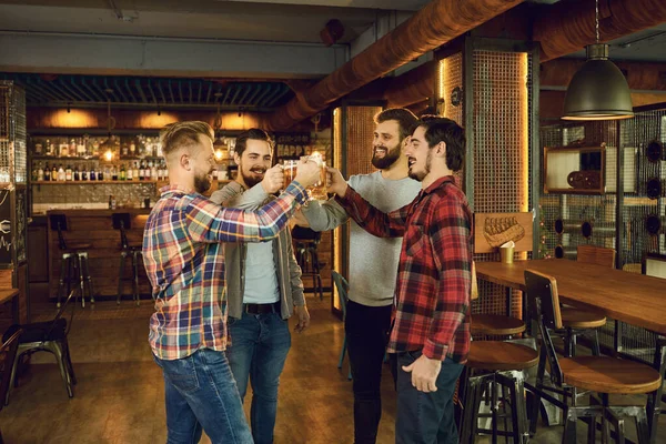 Group of happy friends clinking glasses with beer at a sports bar. — 스톡 사진