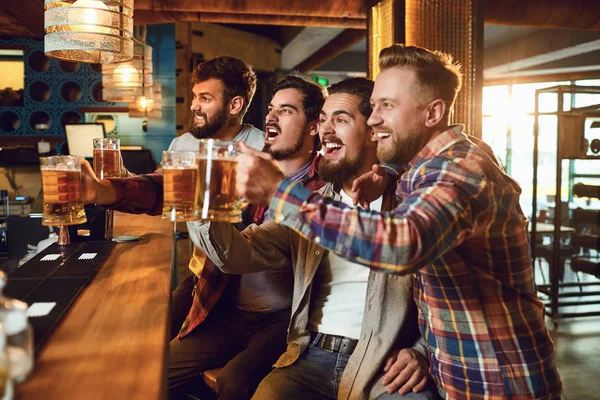 Un grupo de chicos viendo deportes en la televisión en un bar . — Foto de Stock