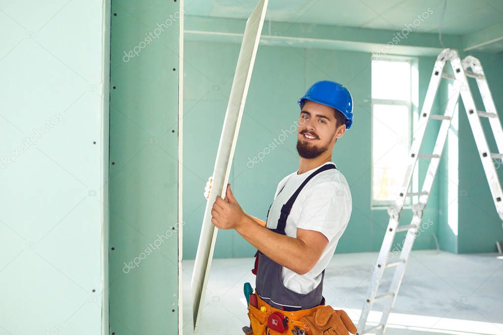 Worker builder installs plasterboard drywall at a construction