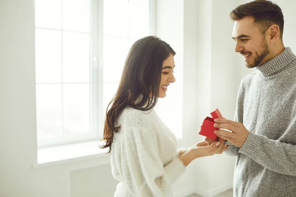 El tipo le hace una propuesta de matrimonio a la chica. Sonriente hombre da una propuesta de matrimonio anillo de en la habitación . — Foto de Stock